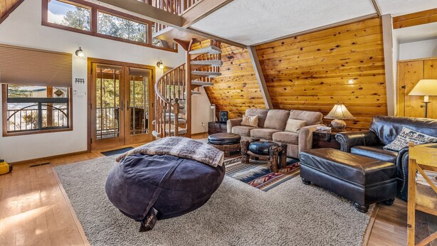 Un salón espacioso con una escalera de madera, un gran ventanal y una zona de estar acogedora.