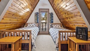 Un dormitorio acogedor en el ático con dos camas de madera, una mesita y una radio.