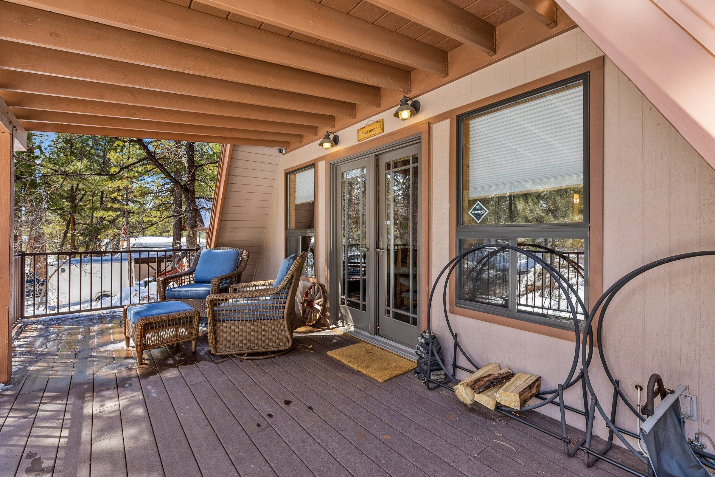 A covered porch with wicker furniture, a bicycle rack, and a view of the outdoors.