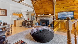 Una sala de estar acogedora con chimenea, techo de madera y televisor.