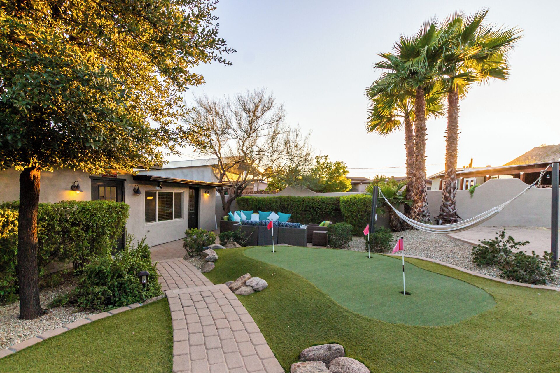 A well-maintained backyard with a patio, seating area, and a small putting green.