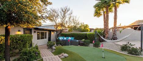 A well-maintained backyard with a patio, seating area, and a small putting green.