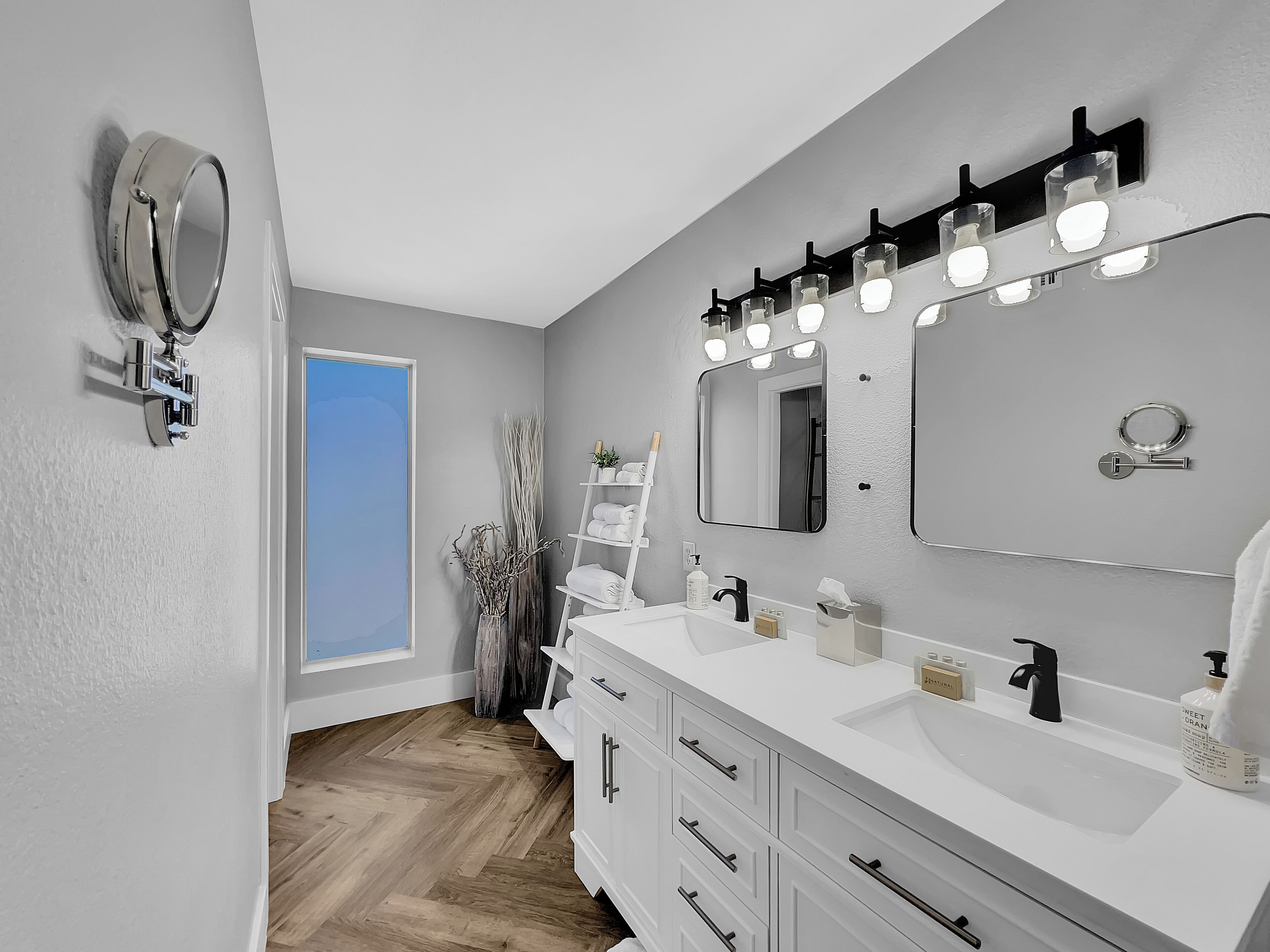 A modern bathroom with two sinks, a large mirror, and a vanity with drawers.