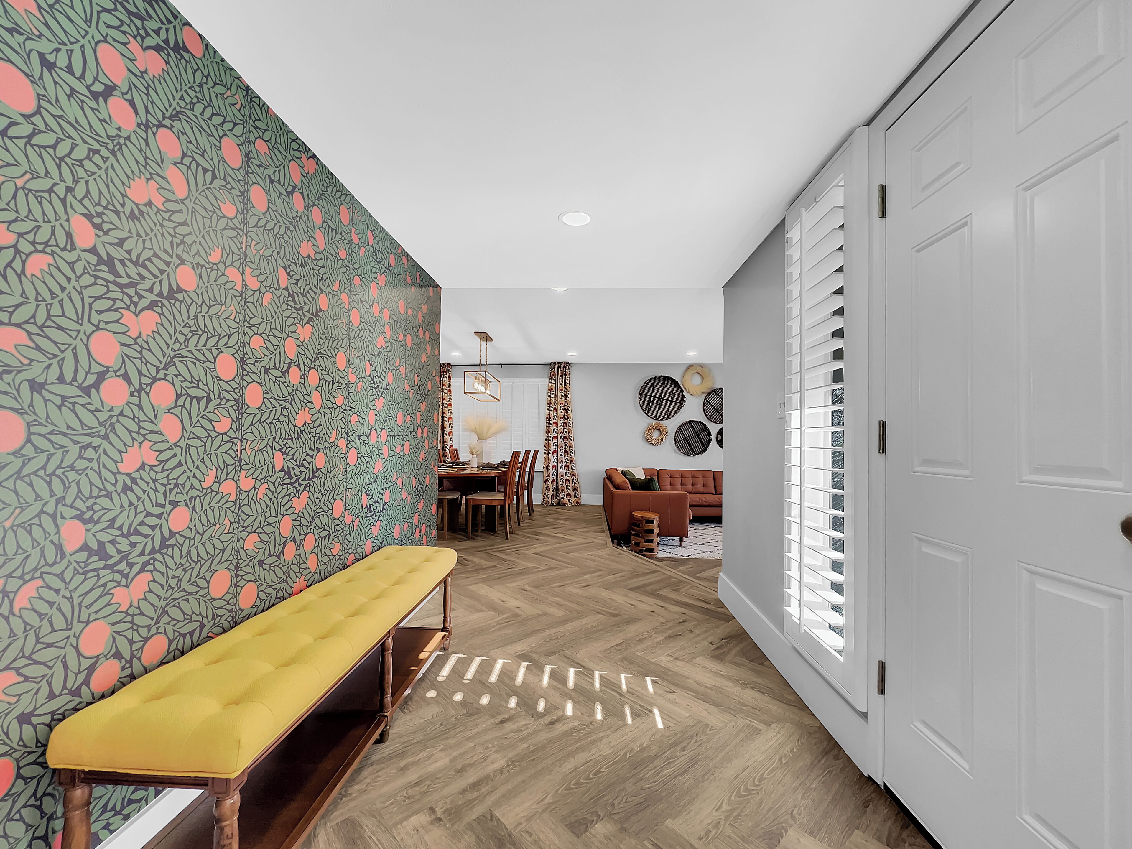 A hallway with a bench, a dining area, and a living room.