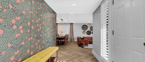 A hallway with a bench, a dining area, and a living room.