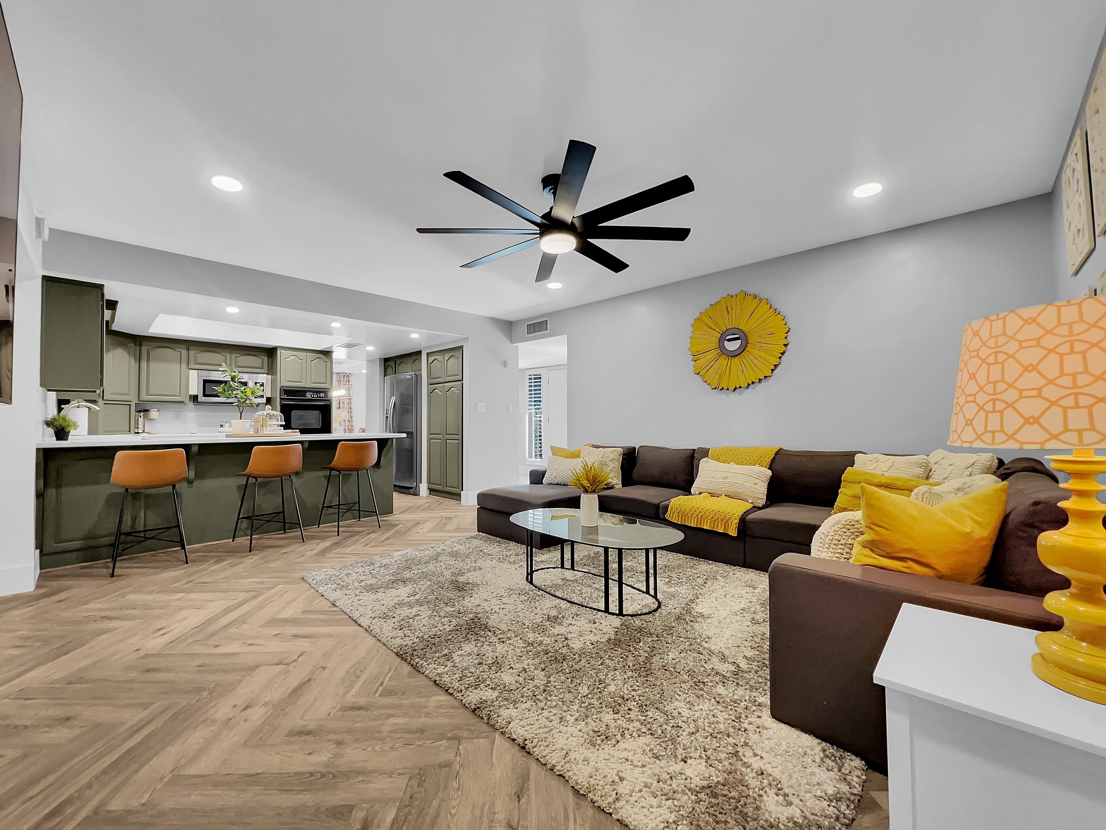 A modern living room with a brown sofa, a coffee table, and a ceiling fan.