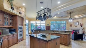 A spacious kitchen with wooden cabinets, a large island, and hanging pots. - Tonto Chandler (Chandler)