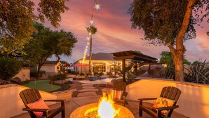 An outdoor patio with a fire pit, two chairs, and a pool area. - Tonto Chandler (Chandler)