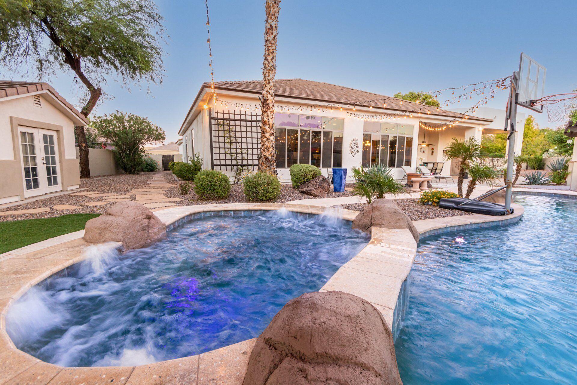 A residential property with a swimming pool, a hot tub, and a patio area.