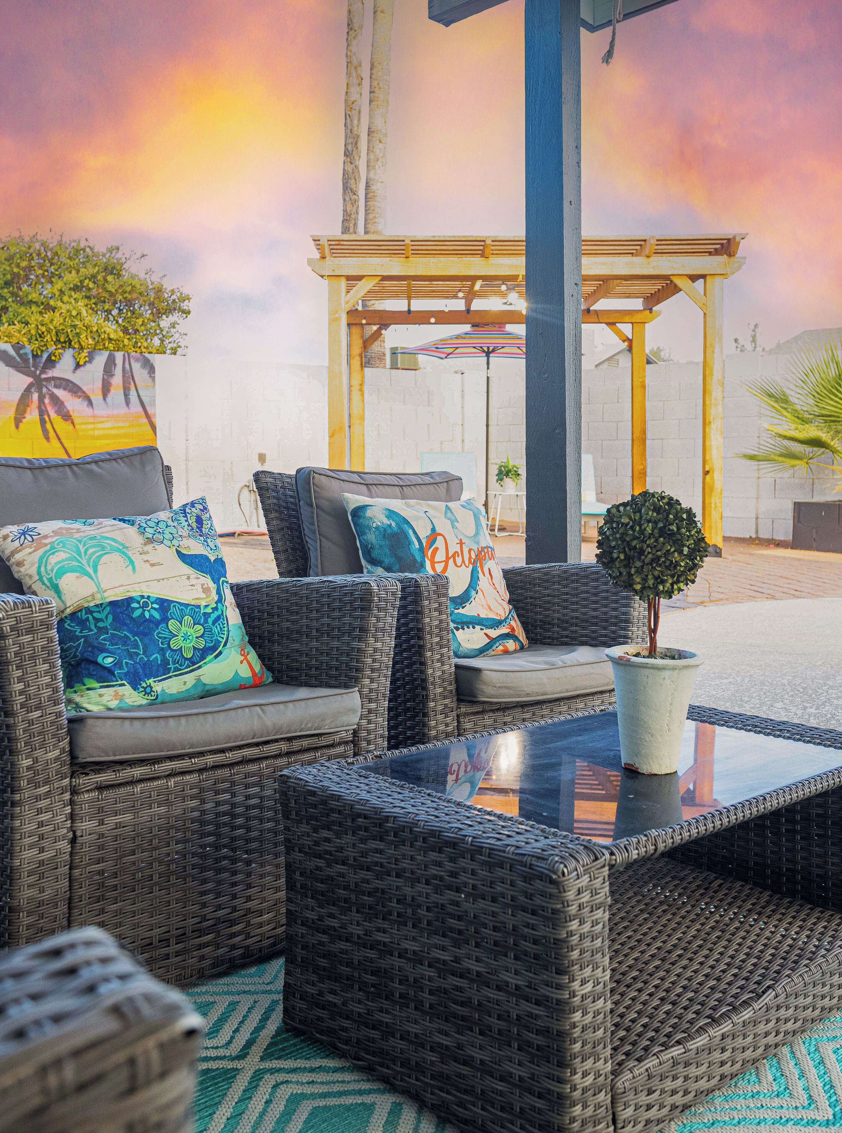 A wicker outdoor seating area with cushions and a small potted plant.