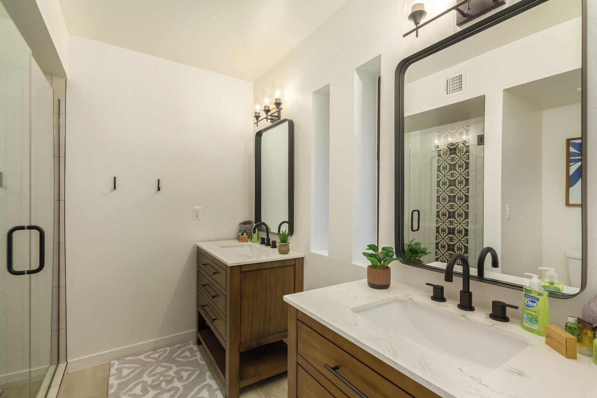 A modern bathroom with a large mirror, a sink with a marble countertop, and a shower area.