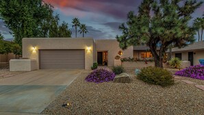 A modern house with a garage, a landscaped front yard with pebbles and flowers, and a tree. - Beverly Scottsdale (Scottsdale)