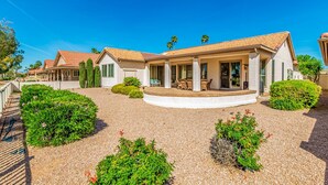 A two-story house with a covered patio, surrounded by well-maintained gardens and palm trees. - Michigan Sun Lakes (Chandler)
