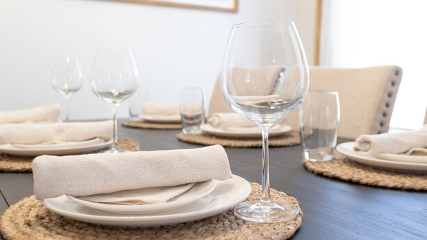 A dining table set with white plates, folded napkins, and clear wine glasses. - Sonesta Tucson (Tucson)