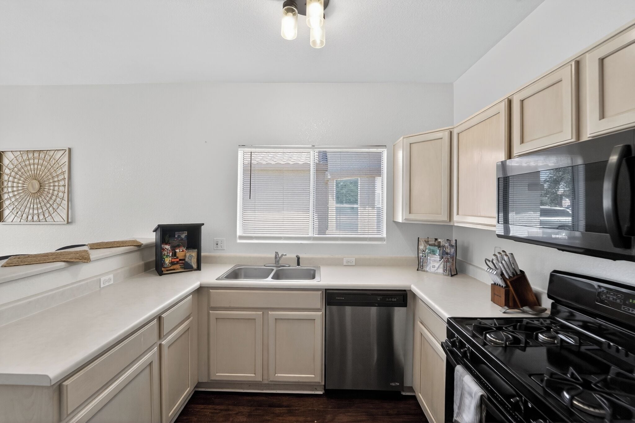 A modern kitchen with white cabinets, a dishwasher, a stove, and a microwave.