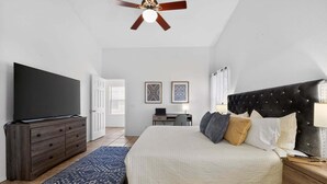 A bedroom with a bed, a TV, a dresser, a ceiling fan, and a desk with a chair. - Sonesta Tucson (Tucson)