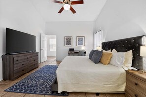 A bedroom with a bed, a TV, a dresser, a ceiling fan, and a desk with a chair. - Sonesta Tucson (Tucson)