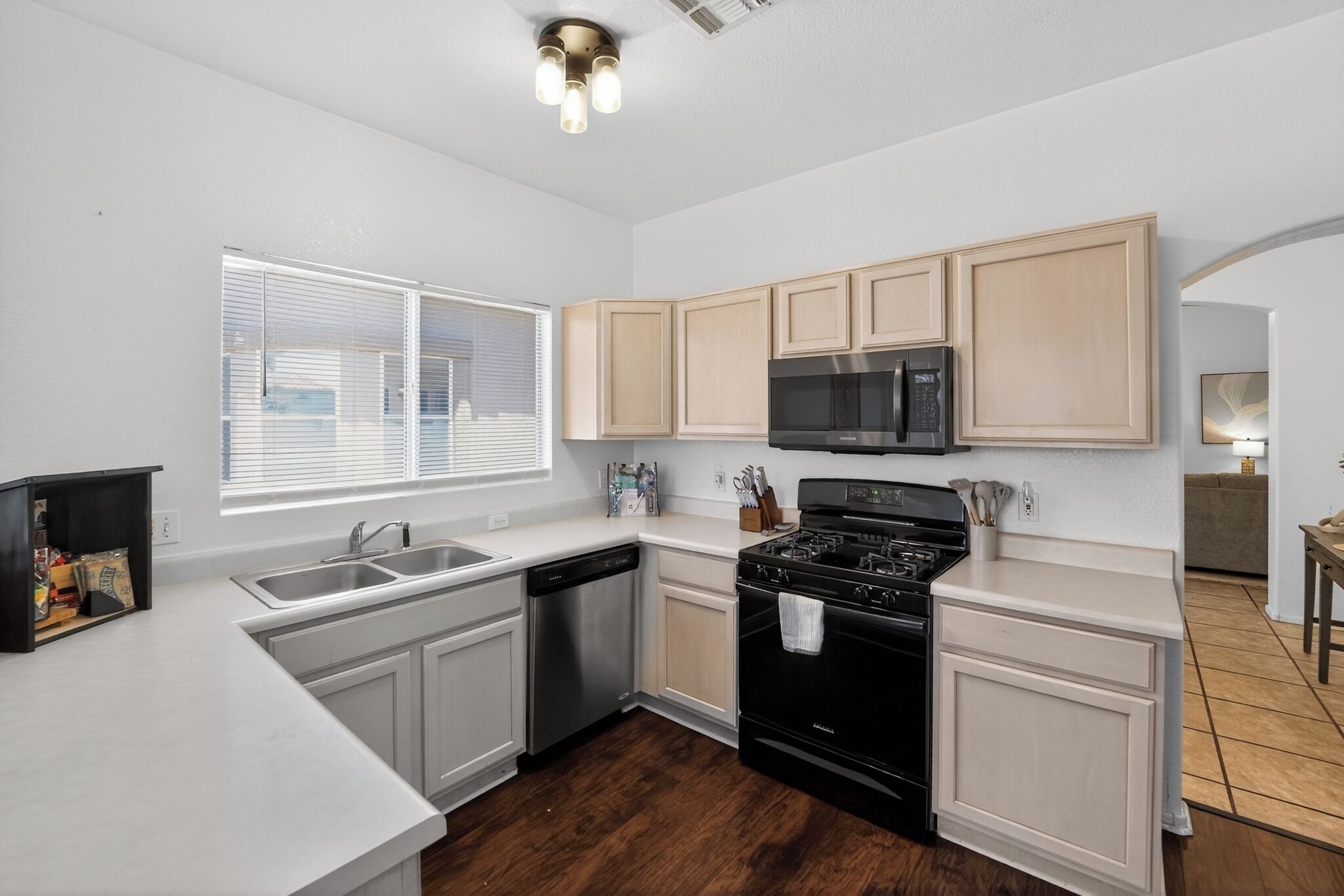 A modern kitchen with white cabinetry, a black stove, stainless steel dishwasher, and a microwave.