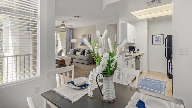 A modern kitchen with white cabinets, a black refrigerator, and a dining area with a table set for two. - Sahuaro #2035 Scottsdale (Scottsdale)