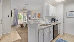 A modern kitchen with white cabinets, a granite countertop, and a dishwasher. - Sahuaro #2035 Scottsdale (Scottsdale)
