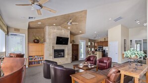 A spacious living room with a fireplace, leather furniture, and a kitchen area visible through an open door. - Sahuaro #2035 Scottsdale (Scottsdale)