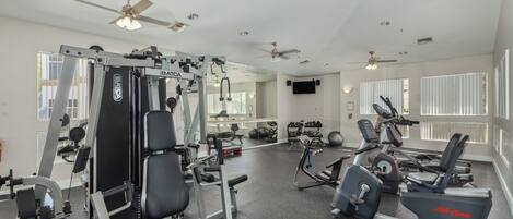 A gym with various exercise equipment, including a weight machine, treadmills, and dumbbells.