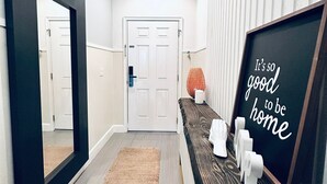 Un pasillo con un banco de madera, un cartel enmarcado y un espejo.