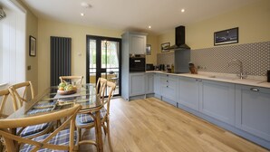 A modern kitchen with light blue cabinets, a glass dining table, and wooden chairs.