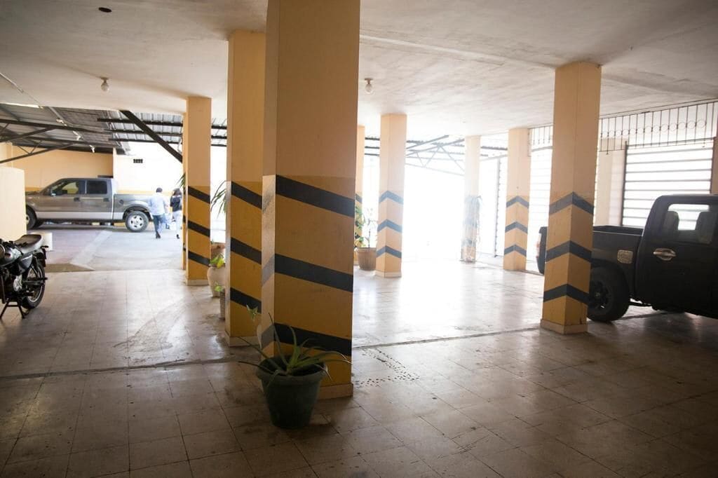Un estacionamiento con pilares amarillos, una motocicleta y una camioneta.