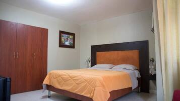 Un dormitorio con cama, armario, mesita de noche y un cuadro en la pared.