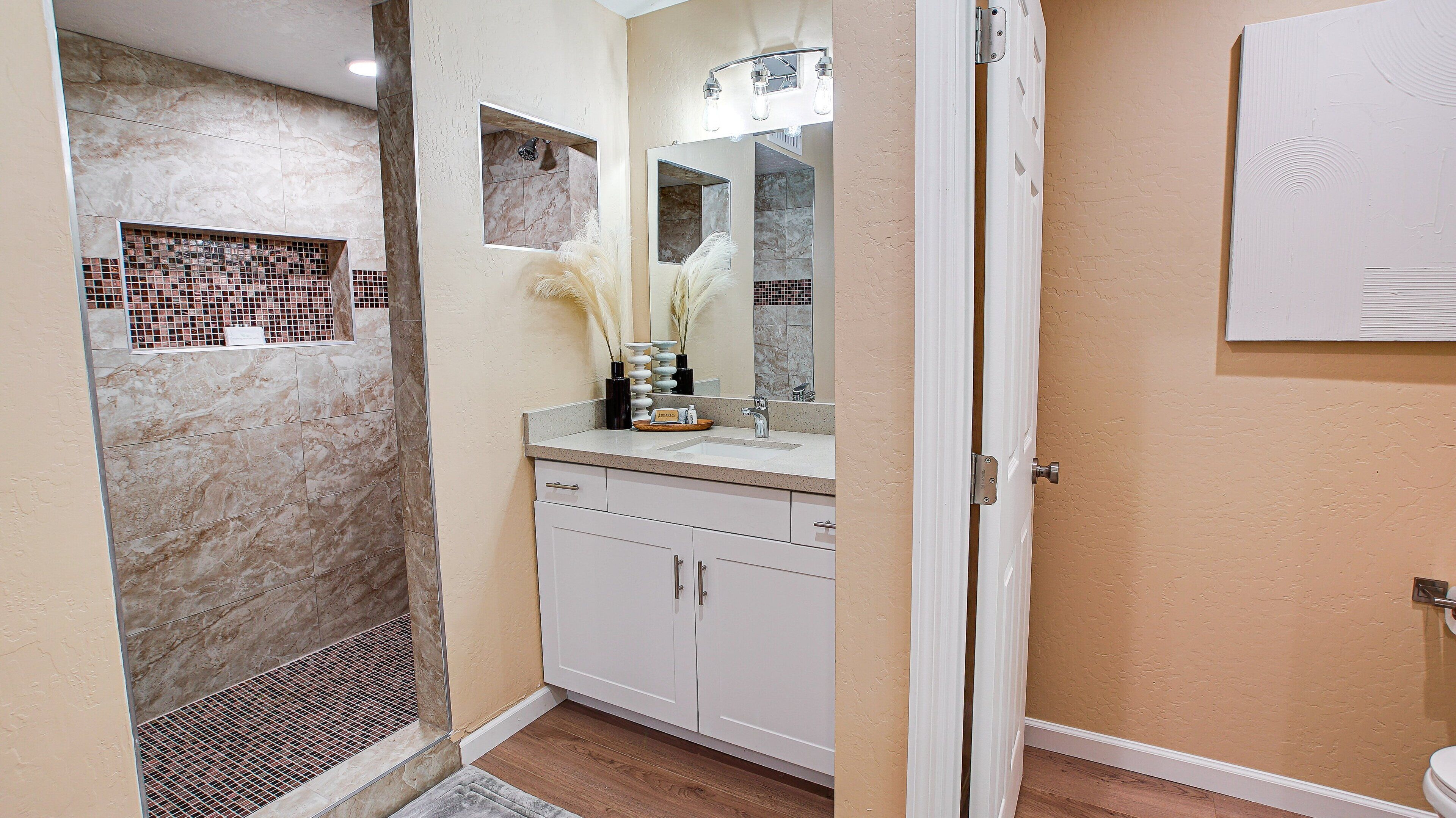 A bathroom with a shower, a sink, and a mirror.