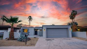 A modern house with a garage, palm trees, and a driveway.