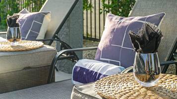 Two wicker lounge chairs with cushions, a woven placemat, and a glass vase with a decorative item.
