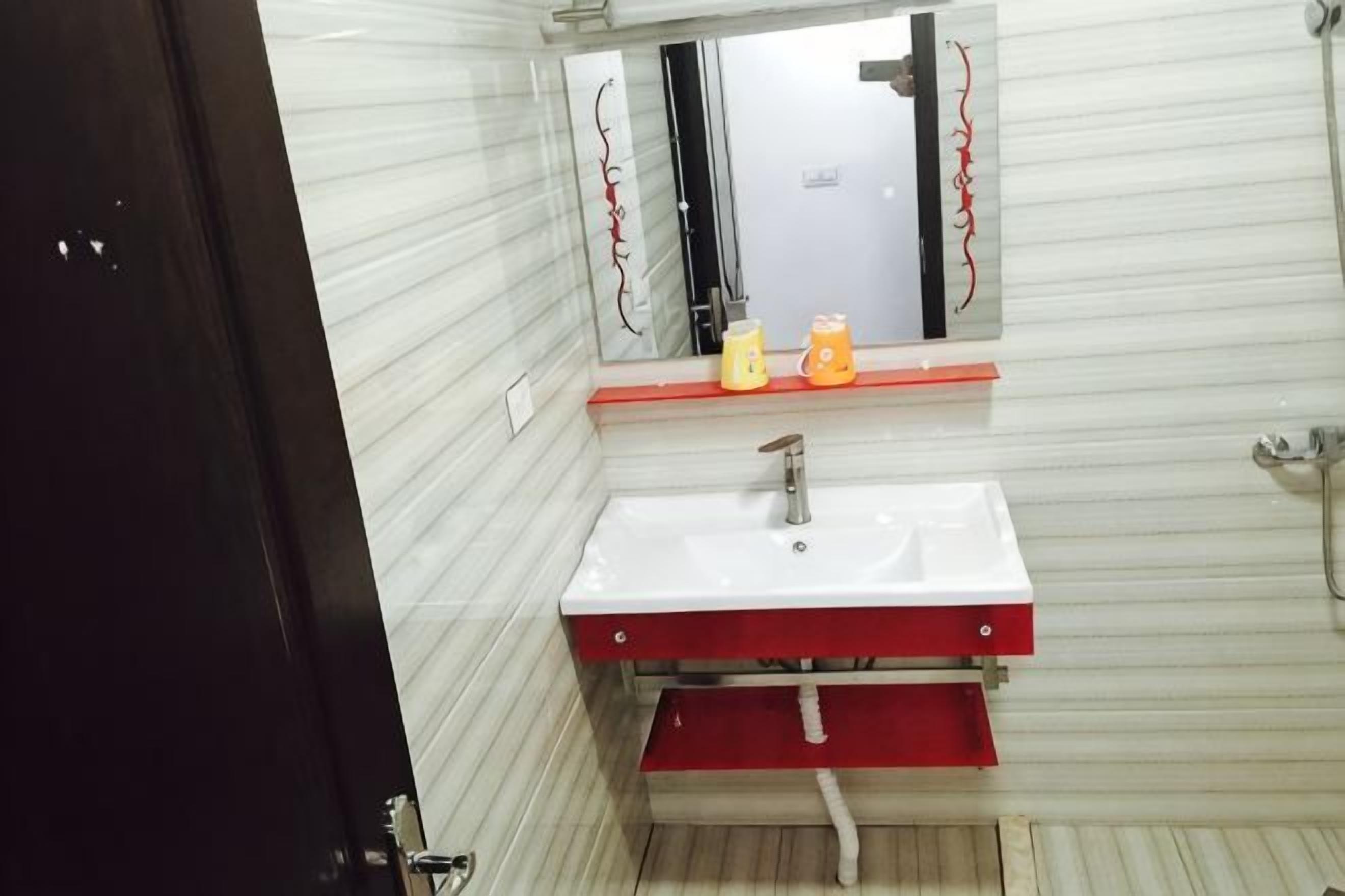 A bathroom with a white sink, red cabinet, and a mirror above it.