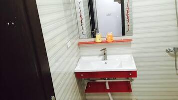 A bathroom with a white sink, red cabinet, and a mirror above it.