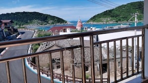 Uma vila costeira com uma igreja imponente, uma estrada serpenteando pela paisagem e vista para o mar.