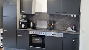 Een koffiezetapparaat/waterkoker, een koelkast, een oven, een kookplaat