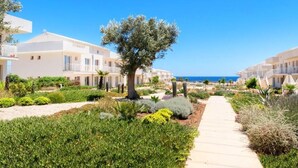 A resort with modern white buildings, a central pathway, and a tree-lined garden.