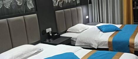 A hotel room with two beds, each with white bedding and blue accents, a grey headboard, and floral wall art.