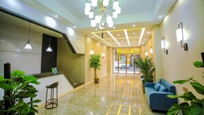 Eine Hotellobby mit Rezeption, Sitzbereich und einer Treppe.