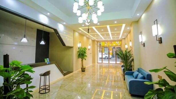 Un hall de hotel con mostrador de recepción, zona de estar y una escalera.
