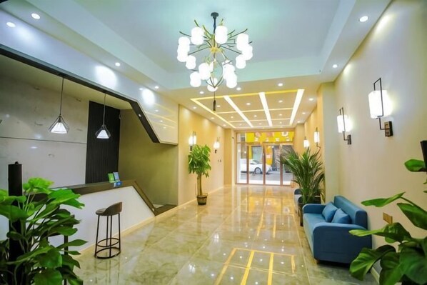 Un hall de hotel con mostrador de recepción, zona de estar y una escalera.