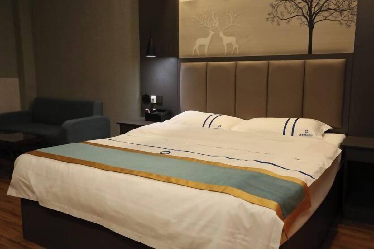 Una habitación de hotel con cama, mesita de noche, lámpara y una silla.