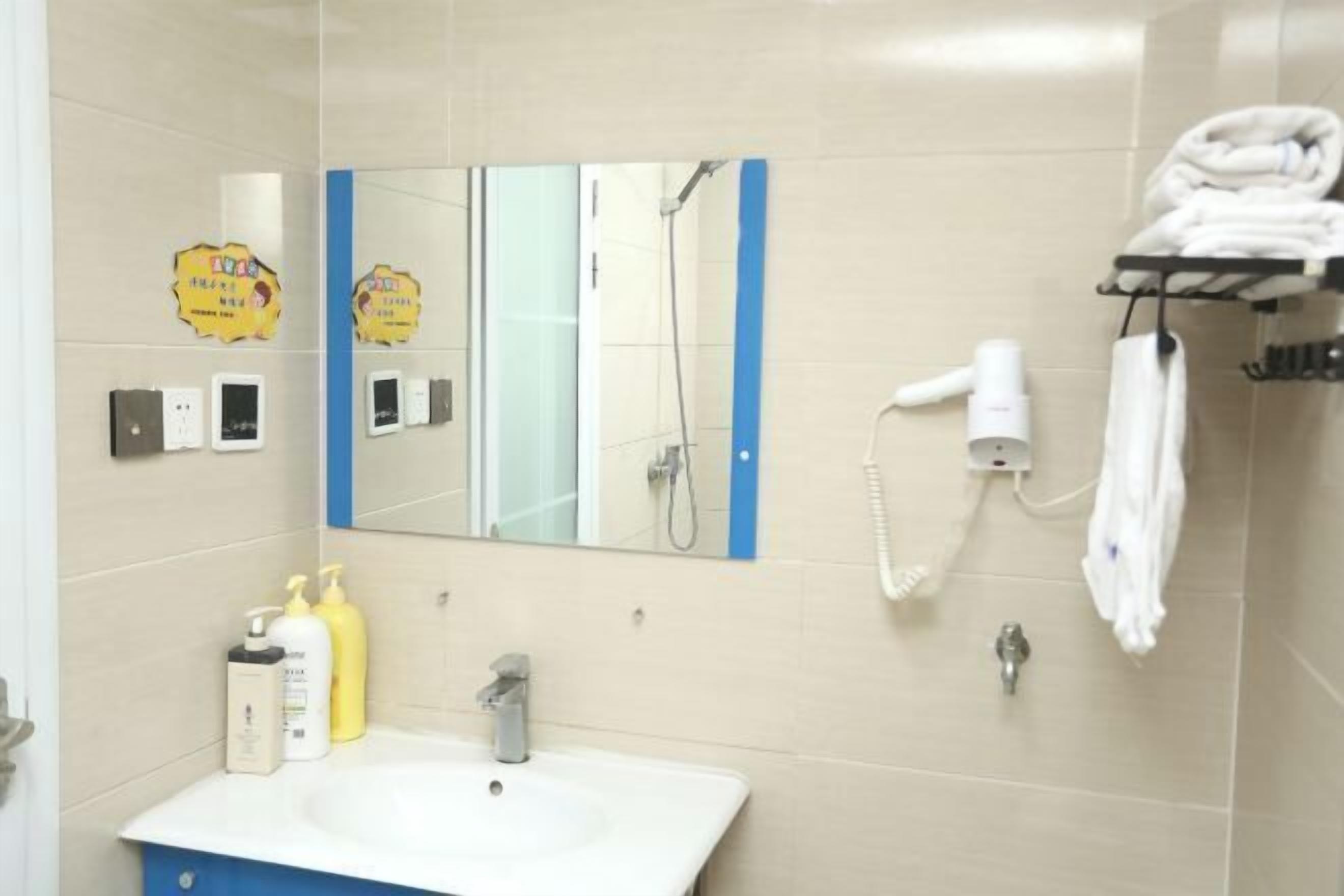 A bathroom with a sink, mirror, towel rack, and toiletries.