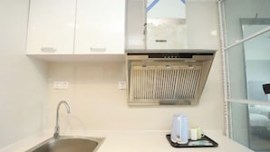 Una cocina moderna con un lavamanos de acero inoxidable, armarios blancos y una campana extractora integrada.