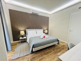 Una camera d'albergo moderna con un letto, abat-jour, una scrivania e un pavimento in legno.