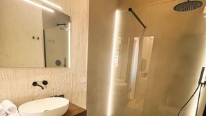 A modern bathroom with a glass-enclosed shower, a white sink, and a large mirror. - Maison Madeleine (La Maddalena)