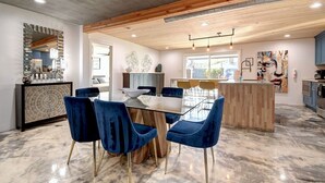Een moderne keuken met houten balken, een eethoek met blauwe stoelen en een marmeren vloer.