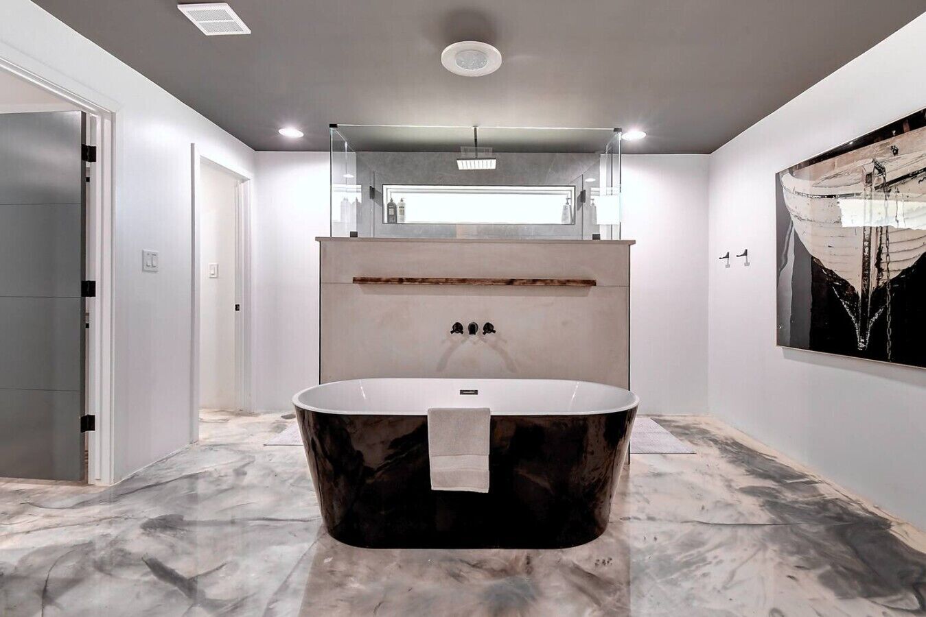 A modern bathroom with a freestanding bathtub, a large mirror, and a marble floor.