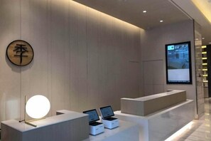 A modern reception area with a wooden wall, a round illuminated sign, and a digital screen displaying information. - JI Hotel (Mudanjiang Railway Station) (Mudanjiang)